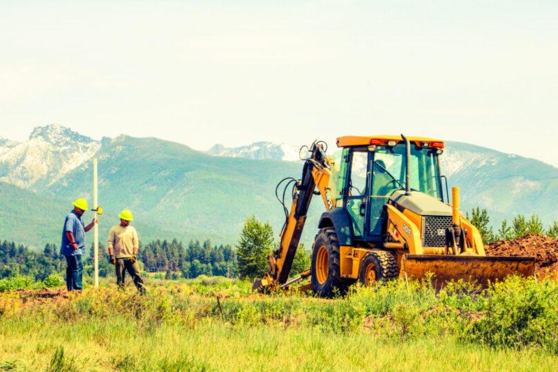 Three men working with a tractor putting in power lines